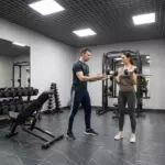Персональный тренер объясняет упражнение клиенту в зале